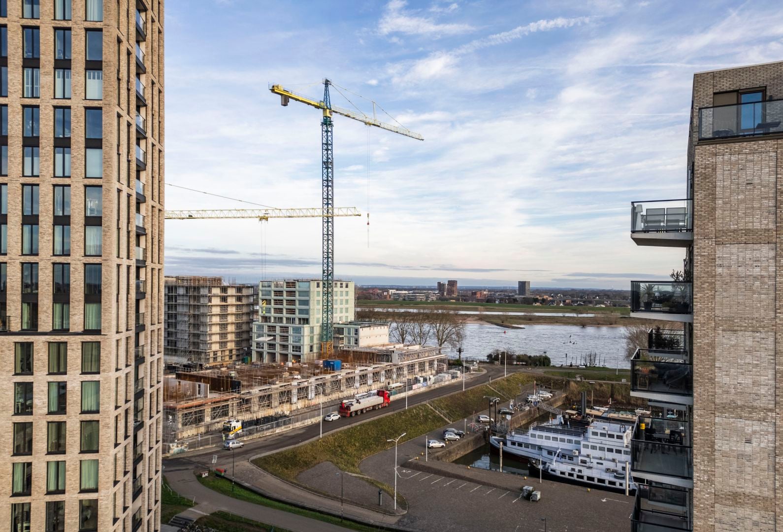 Tussen twee hogen gebouwen is een hijskraan te zien