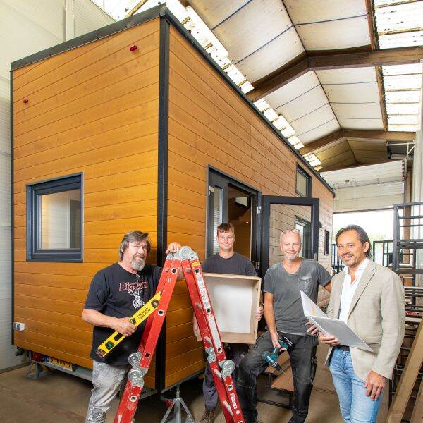 4 mannen die werken aan de bouw van een tiny house
